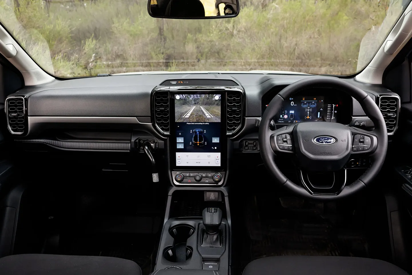 Interior cockpit of a Ford Ranger showing steering wheel, digital driver display, and large vertical touchscreen infotainment system.