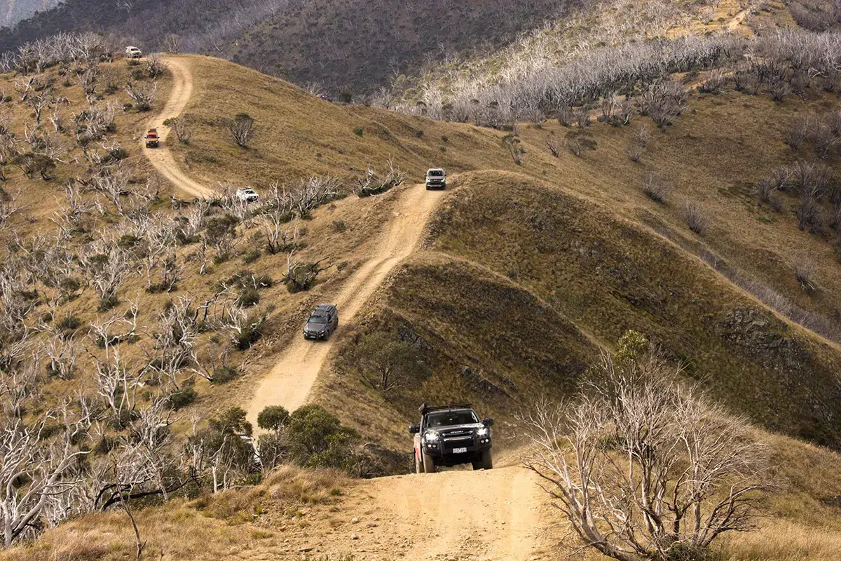 4WD vehicles driving along Blue Rag Range Track in the Victorian High Country with winding mountain trails and rugged alpine terrain.