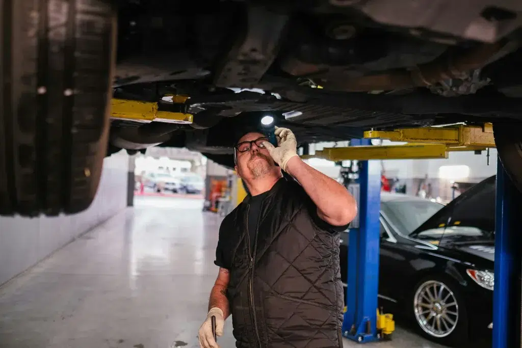 mechanic inspecting a car underneath on a service lift during routine vehicle maintenance