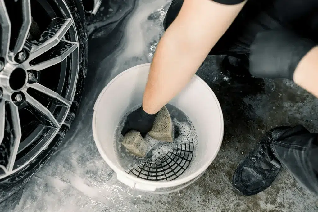 rinsing wash mitt in bucket with grit guard during car wash