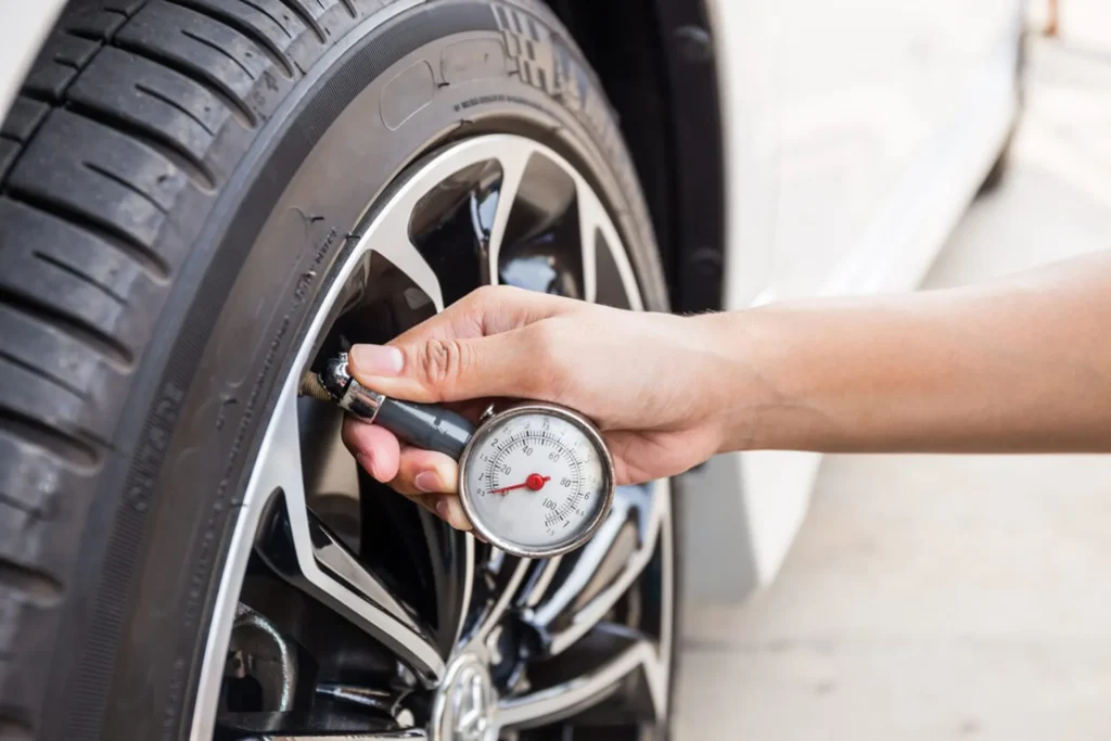 checking car tyre pressure with a gauge to improve fuel efficiency and reduce running costs