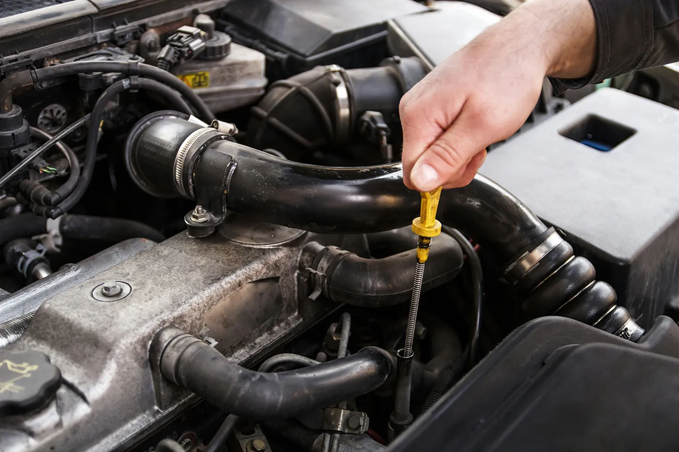 Checking engine oil level with dipstick under the bonnet of a car