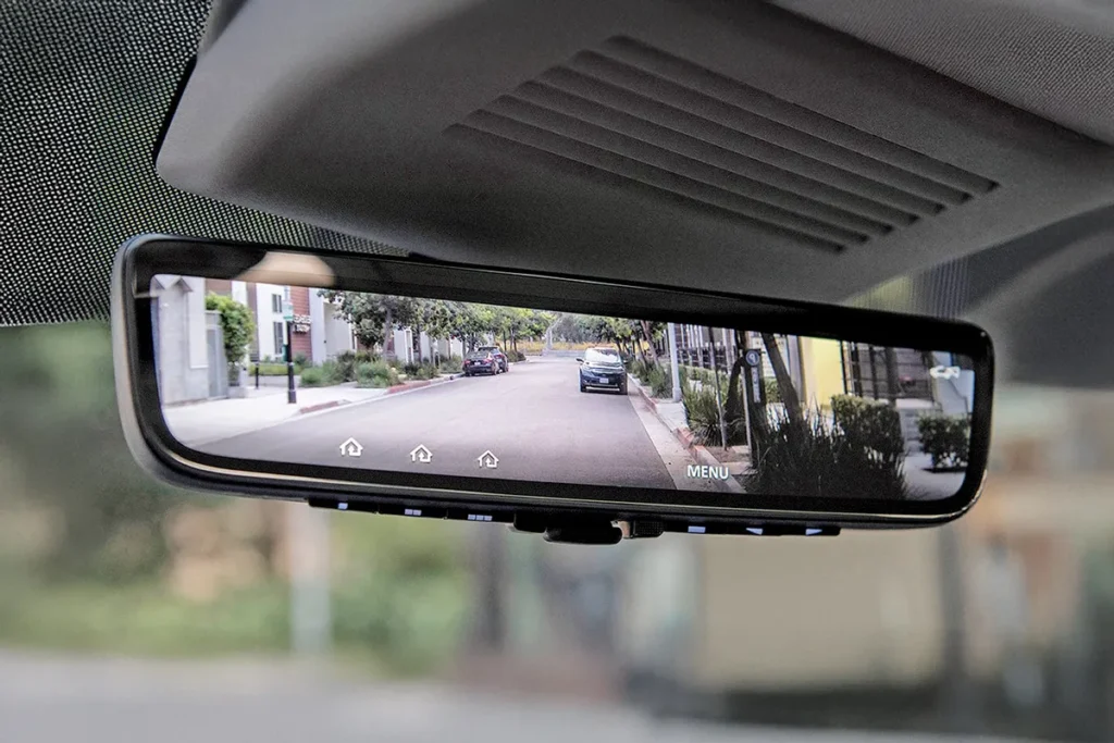 Digital rearview mirror inside a car showing a clear rear view in an urban street environment
