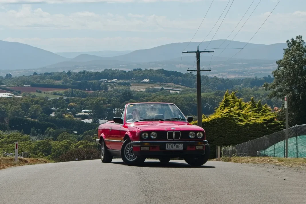 Young driver enjoying a classic convertible on a scenic road in Australia