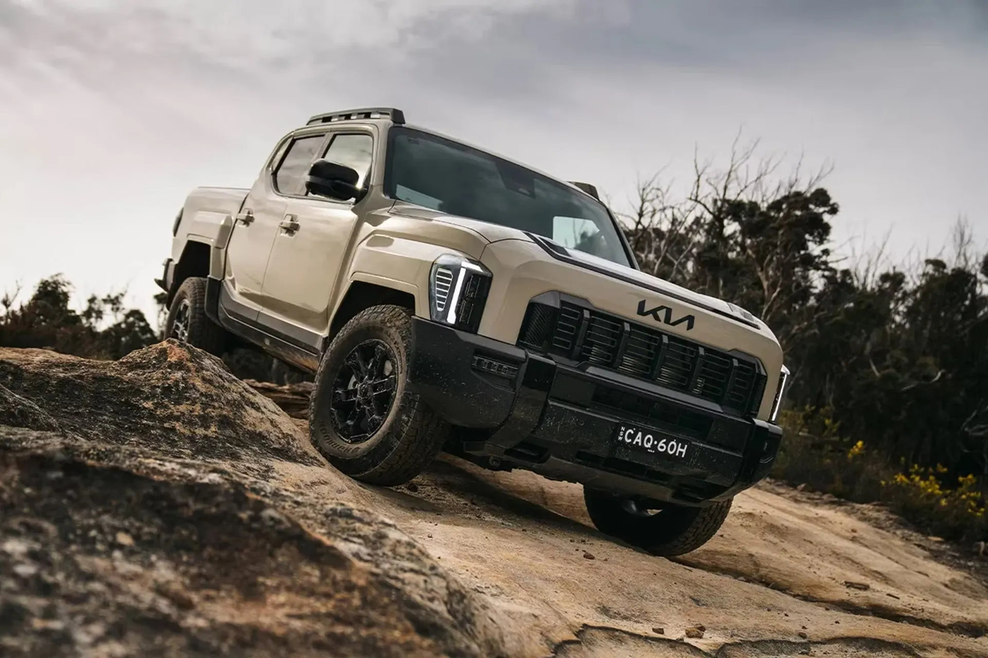 Kia Tasman ute climbing over rocky terrain during off-road testing in Australia for an Australian review.