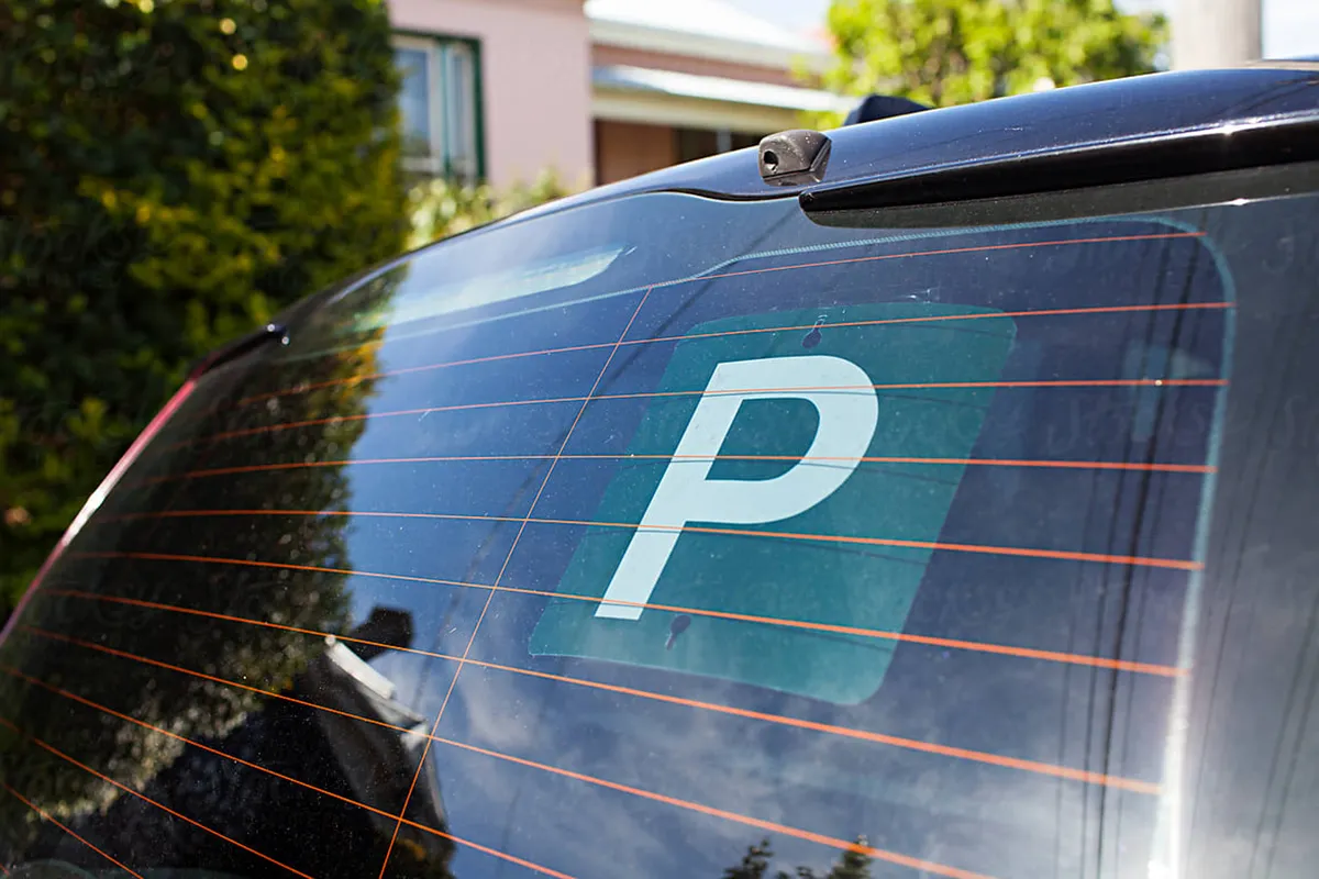 Green P plate displayed on the rear window of a car indicating a provisional driver