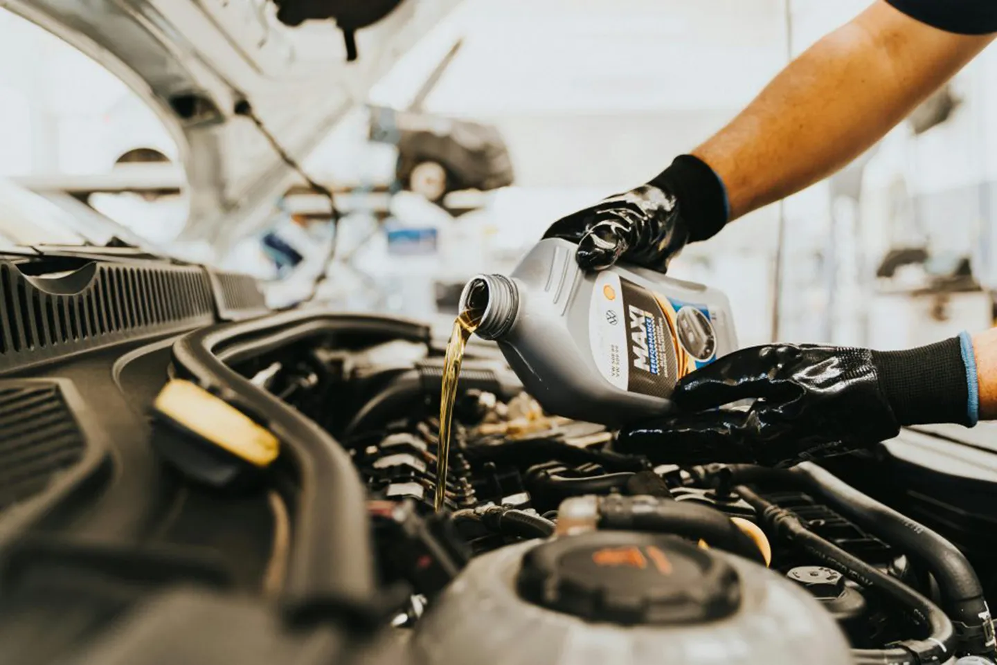 Person pouring engine oil into a car engine during routine vehicle maintenance