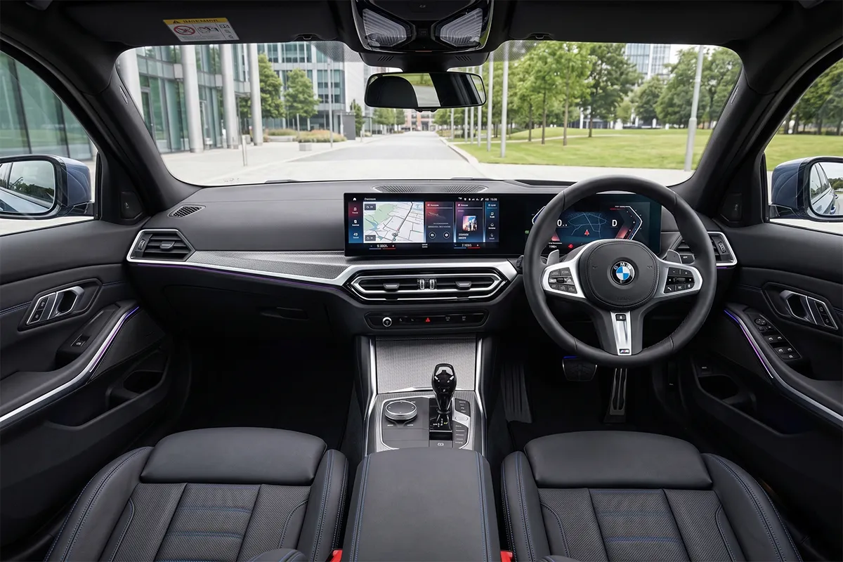 Interior of the 2026 BMW 330i M Sport showing the curved digital display, iDrive controller, and right-hand drive dashboard layout