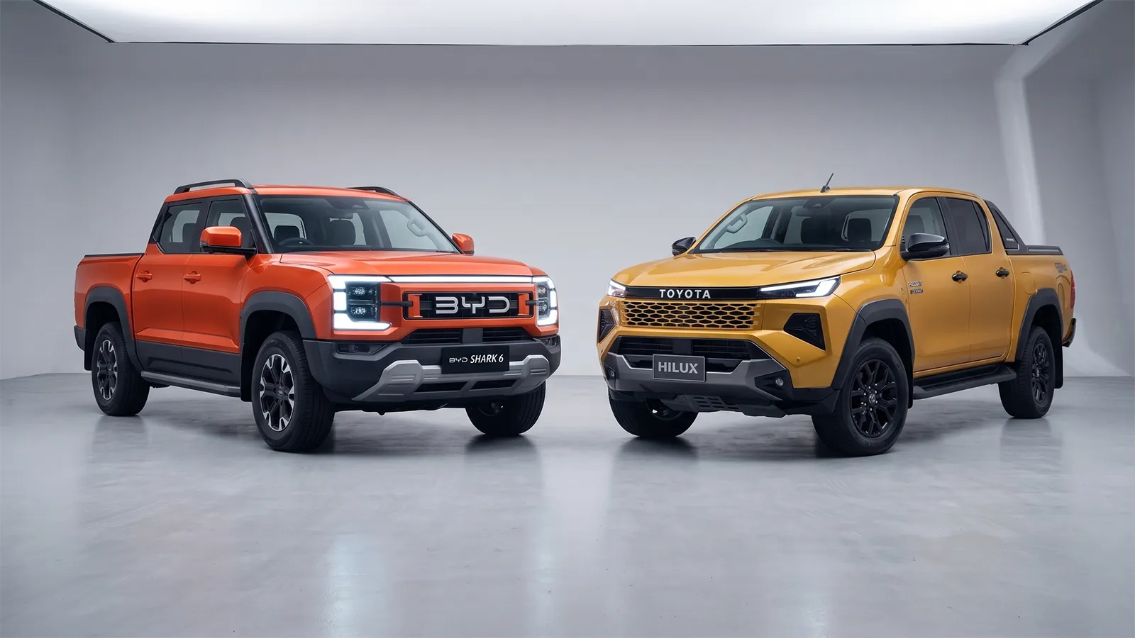 Orange BYD Shark 6 plug-in hybrid ute beside a mustard Toyota HiLux in studio setting, illustrating the new competition Toyota faces in the Australian dual-cab segment