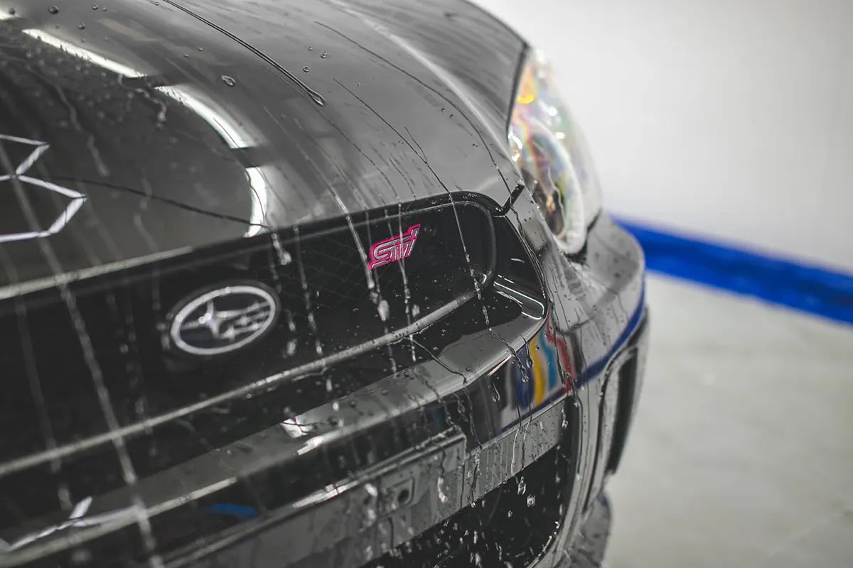 Tight water beading on the front bumper of a black Subaru WRX STI showing the hydrophobic effect of a fresh ceramic coating