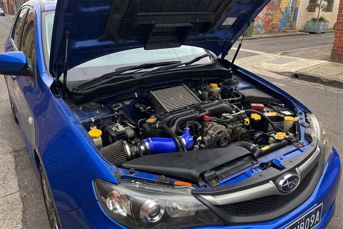 Clean Subaru WRX engine bay with aftermarket cold air intake parked on a Melbourne street