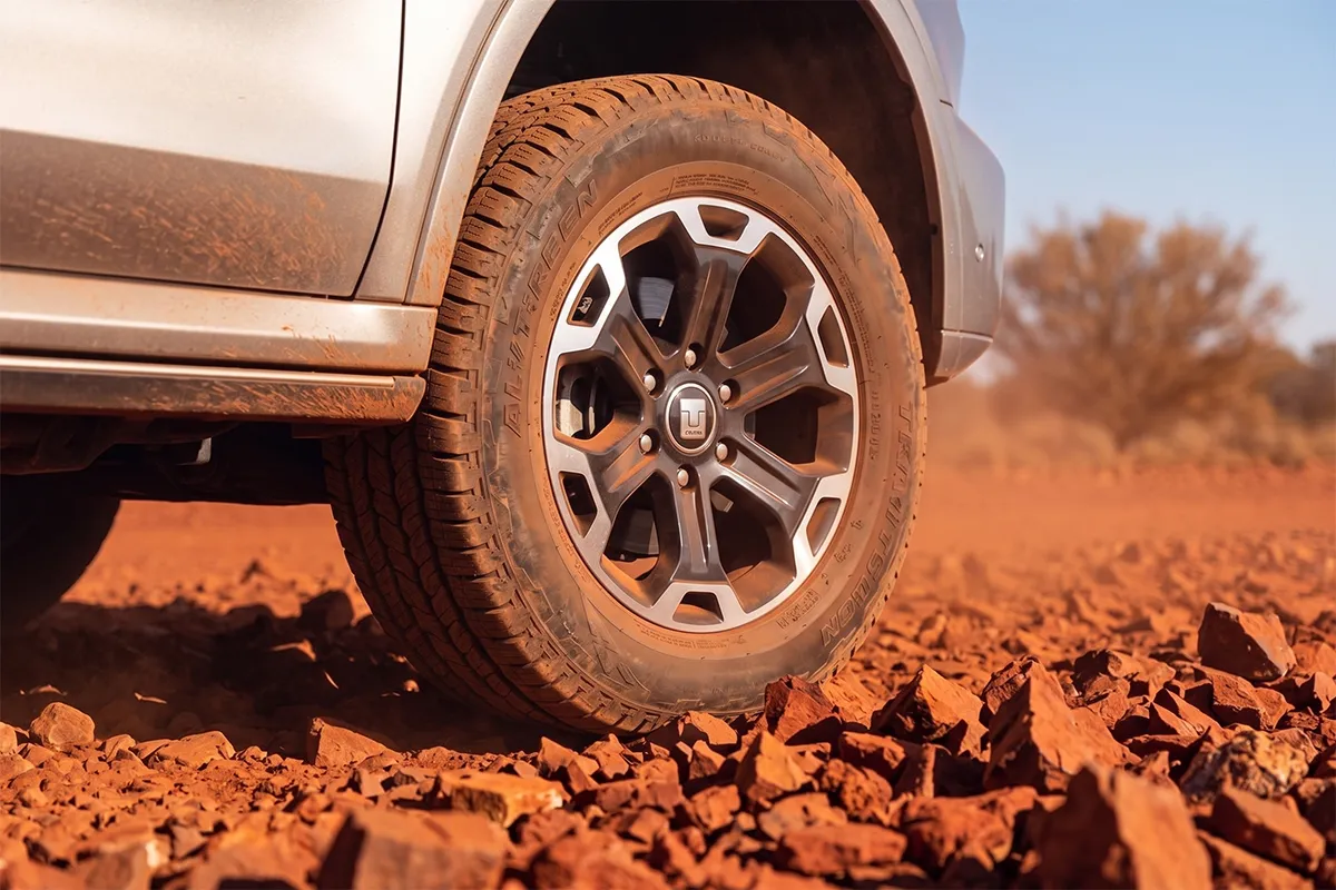 Close-up of a GWM Tank 500 PHEV alloy wheel and light truck tyre on sharp red gibber stones