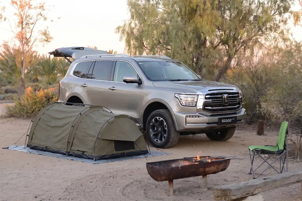 GWM Tank 500 PHEV parked at a remote outback campsite with a swag tent and fire pit at golden hour
