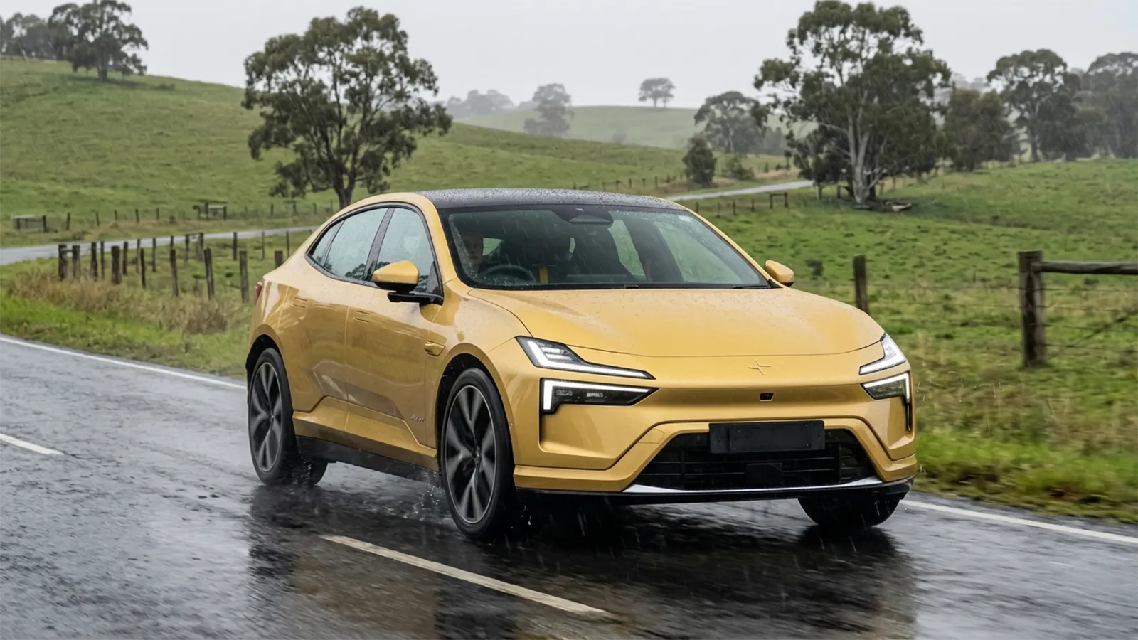Polestar 4 Long Range Dual Motor driving on a wet rural road in Australia surrounded by green pasture and eucalyptus trees