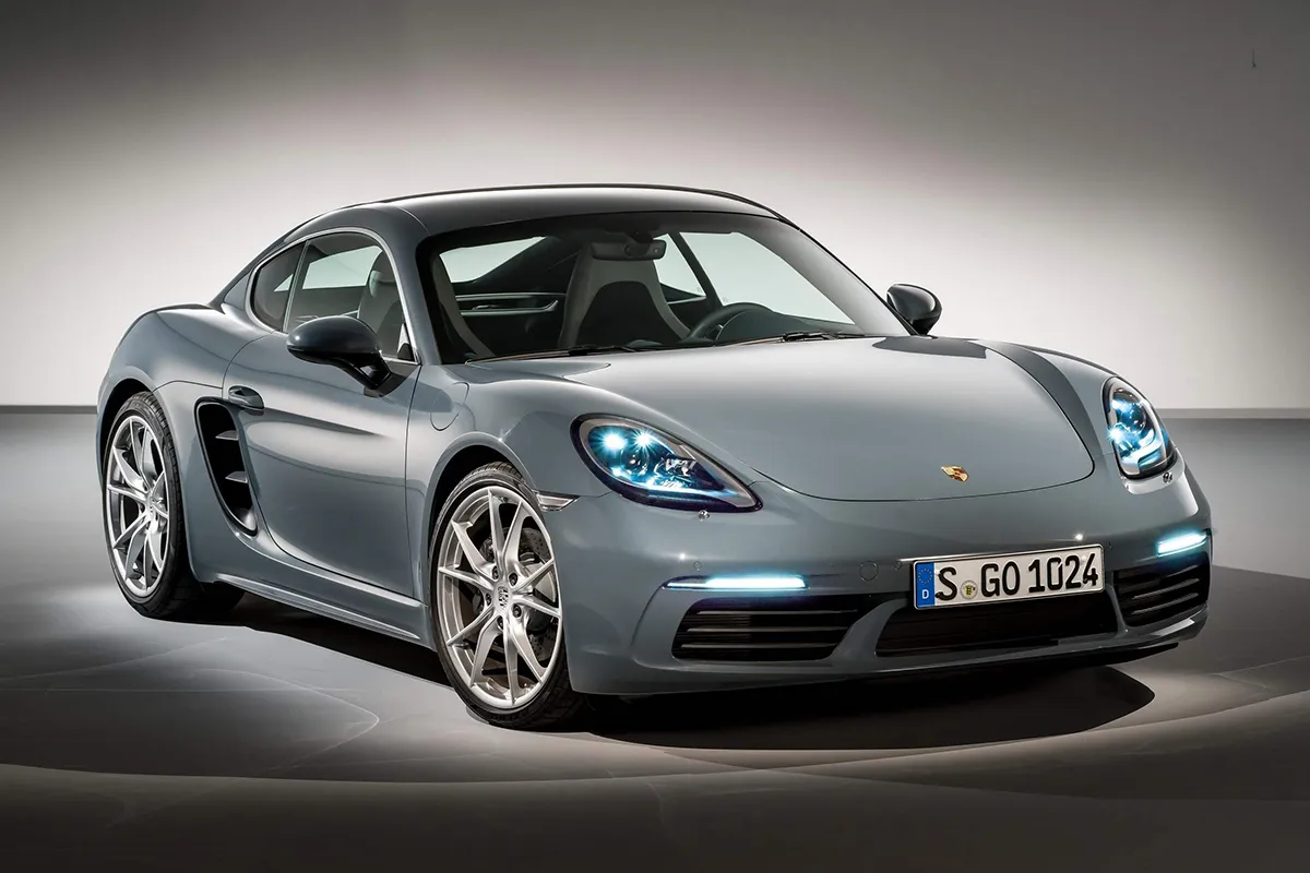 Front three-quarter studio shot of the 2026 Porsche 718 Cayman with headlights illuminated
