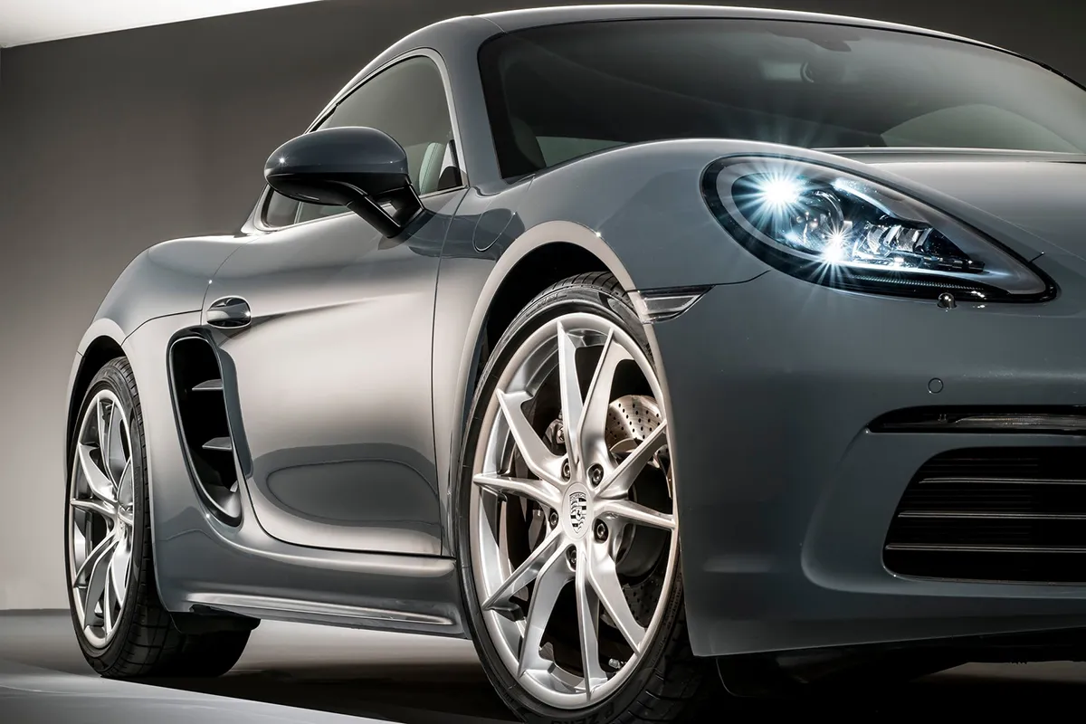 Close-up of the 2026 Porsche 718 Cayman front wheel and side air intake highlighting chassis design