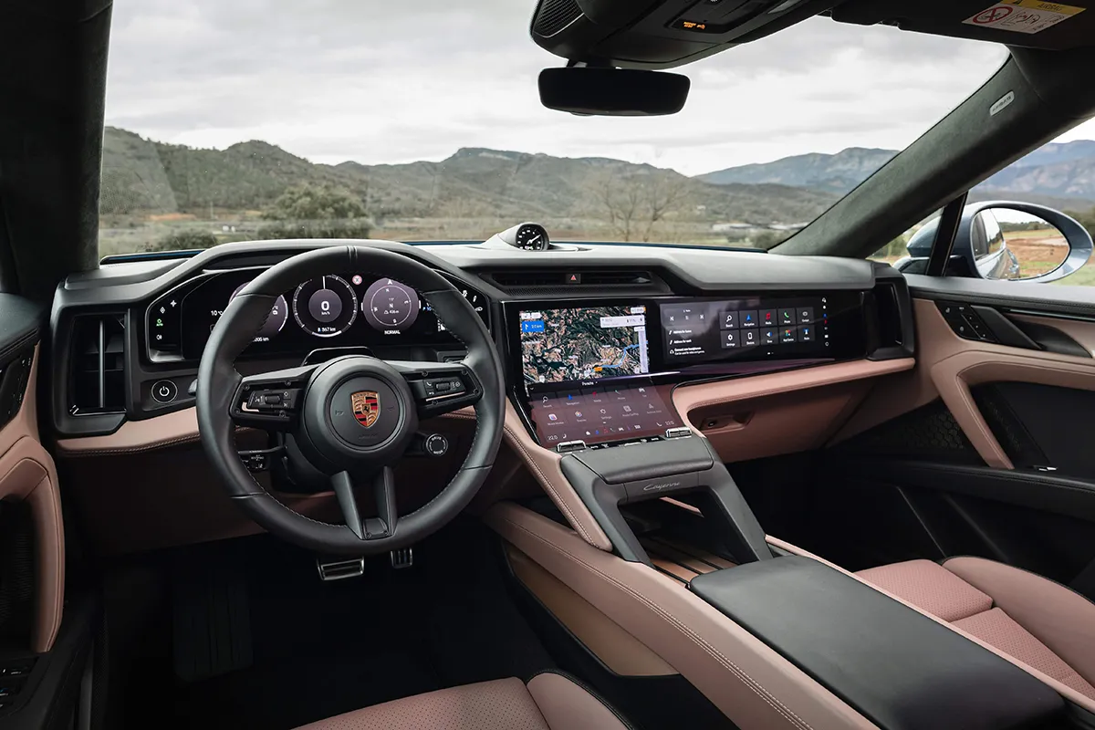 Interior of the new Porsche Cayenne Electric showing the driver-focused dashboard, curved display and steering wheel with physical buttons