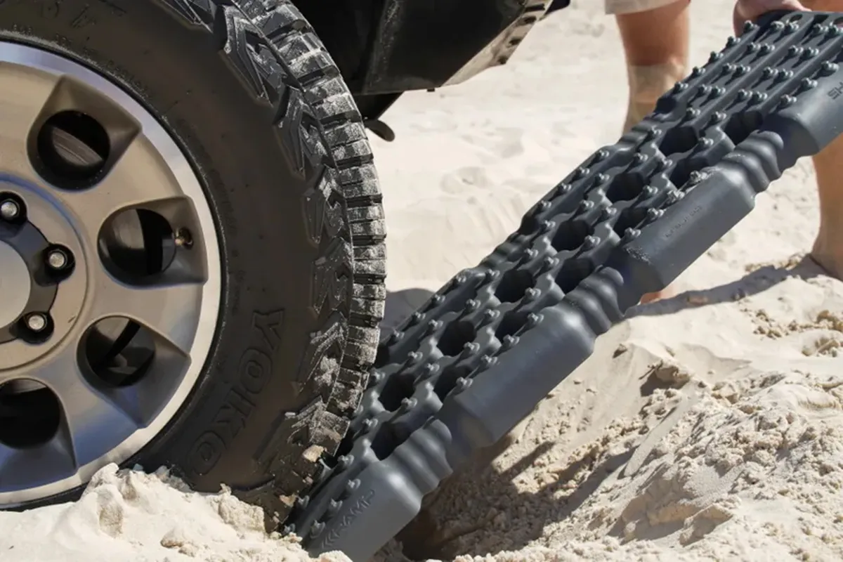 Grey budget recovery board under a 4WD tyre in soft beach sand
