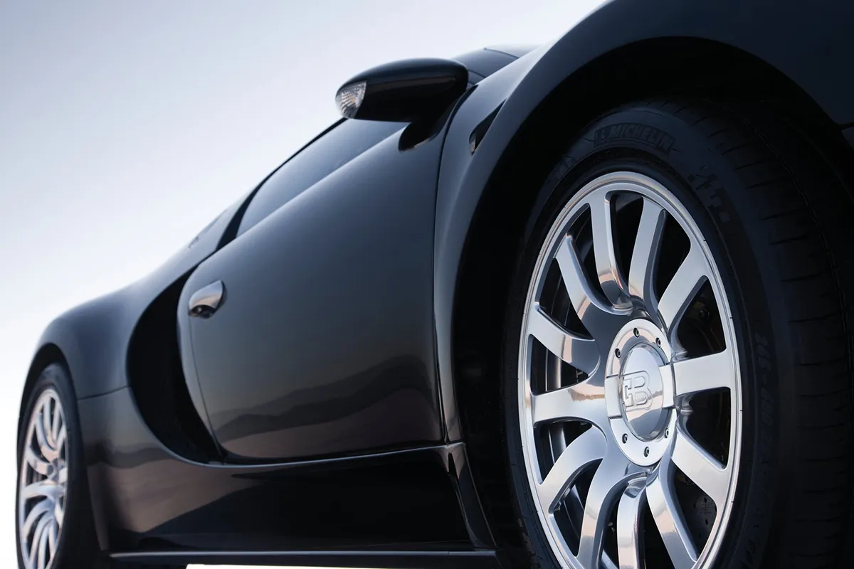 Close detail of the Bugatti Veyron rear haunch, Michelin tyre lettering visible on a wide low-profile tyre with polished multi-spoke alloy wheel and black bodywork