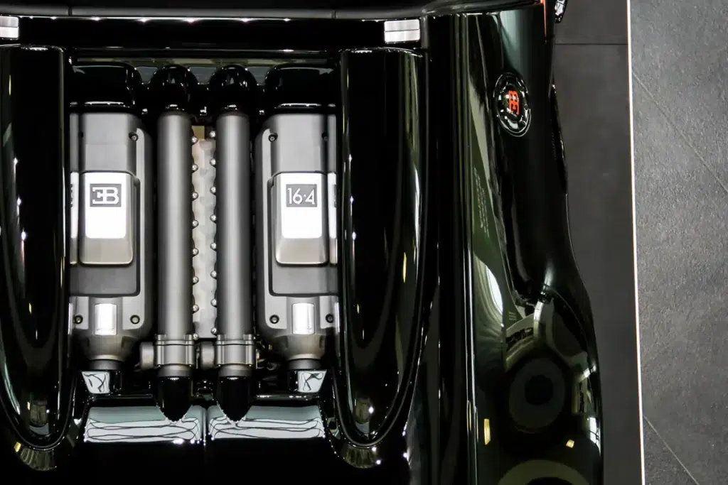 Bugatti Veyron W16 engine bay viewed from above, four turbocharger intercooler towers visible with EB and 16:4 badging, black bodywork surround