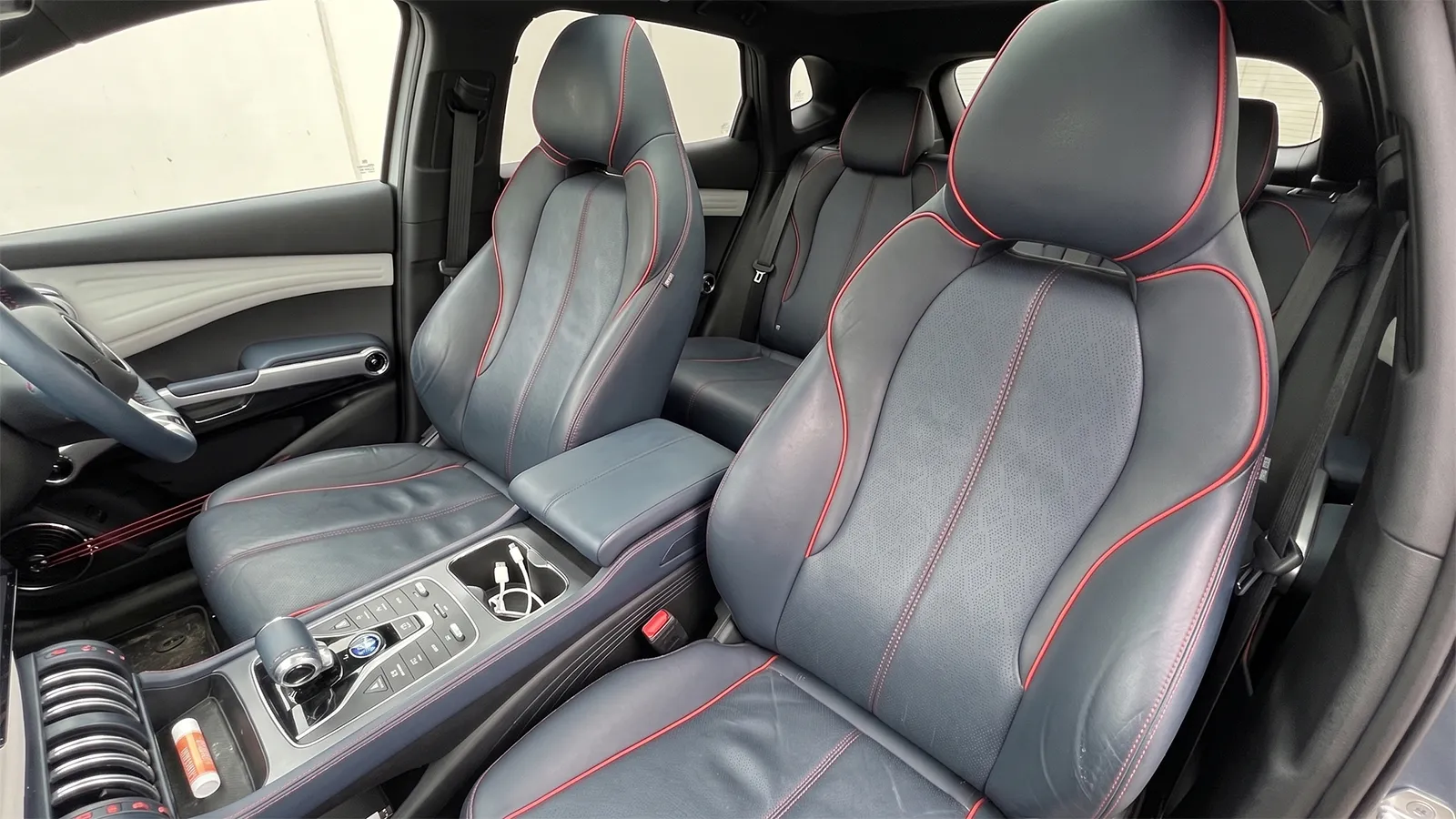 BYD Atto 3 front sports seats in dark synthetic leather with red contrast stitching, showing light creasing after two years' use