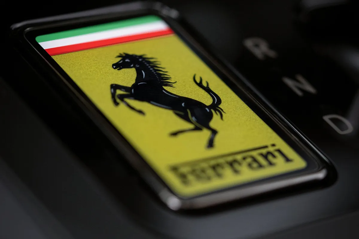 Close-up of the Ferrari Luce E Ink key showing the prancing horse logo in yellow, docked beside the gear selector