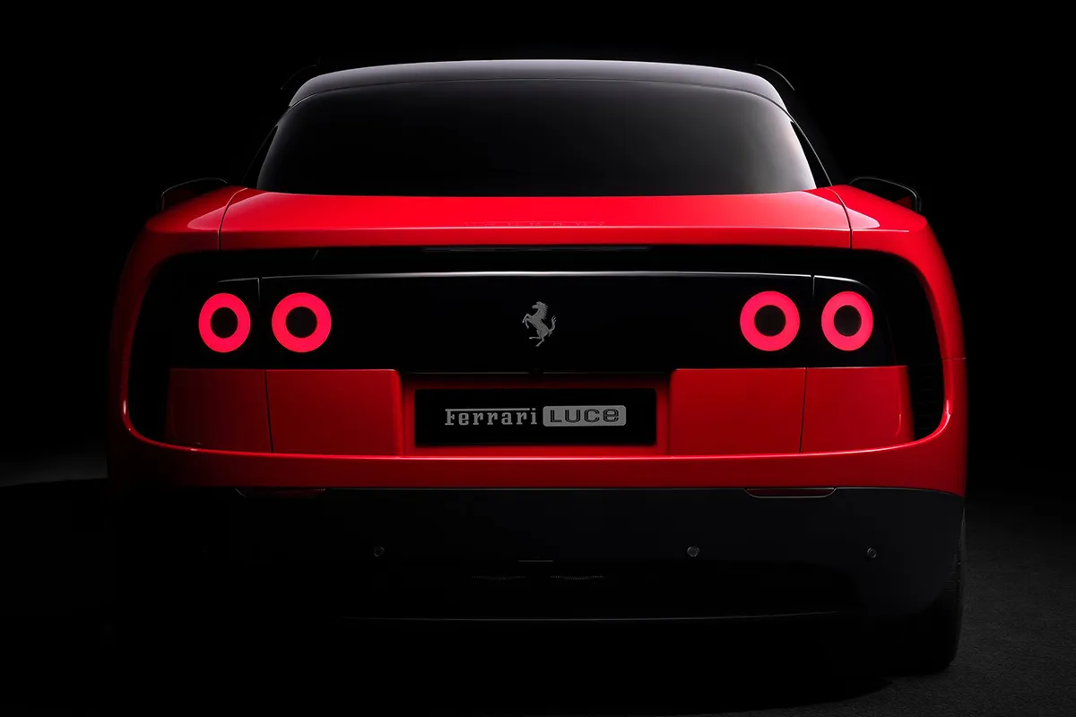 Ferrari Luce rear in red on black background, four circular halo tail-lights illuminated and prancing horse badge centred