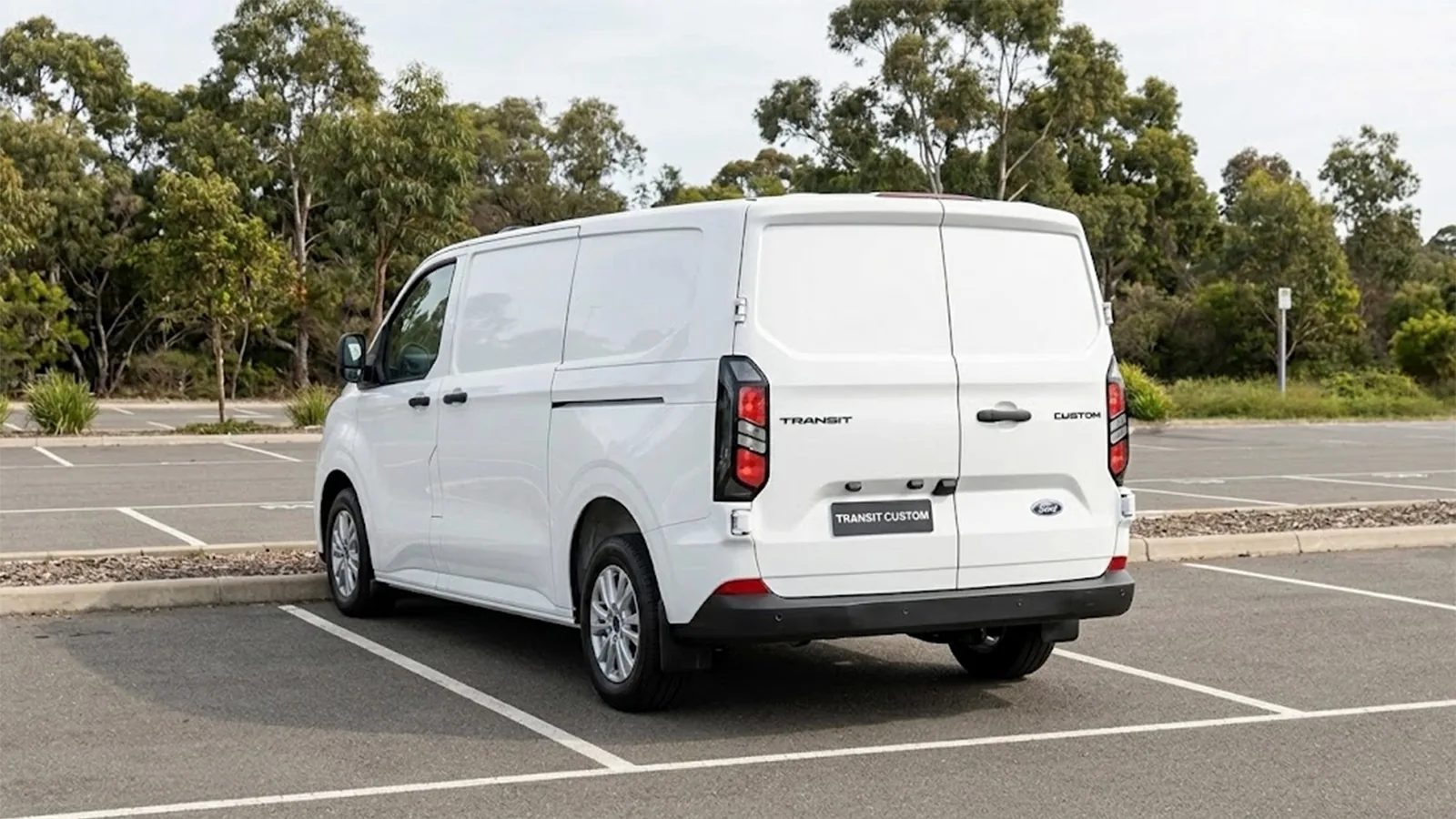 Rear three-quarter view of a white Ford Transit Custom showing the split barn doors and Transit Custom badging
