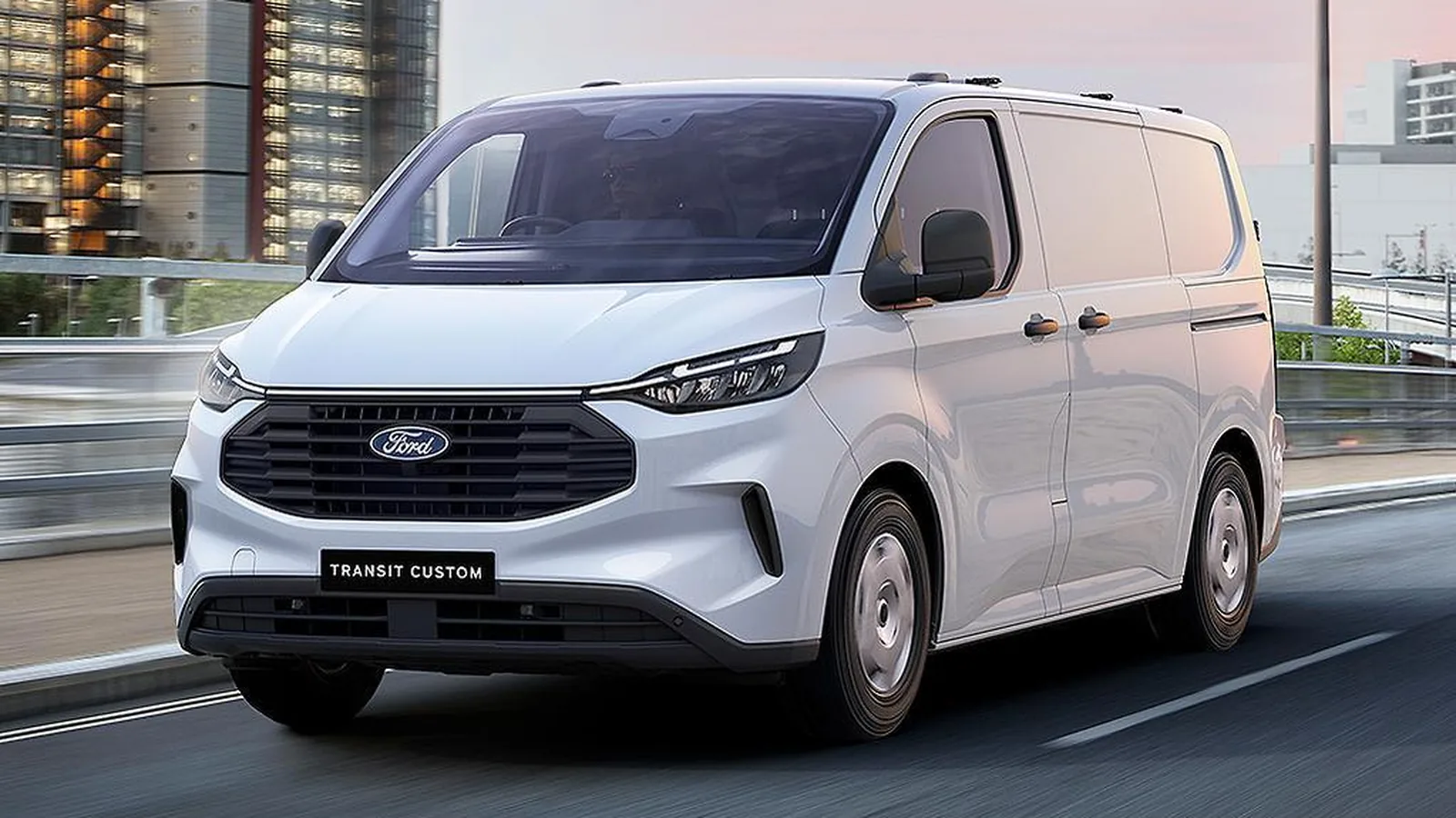 White Ford Transit Custom driving on an urban road, front three-quarter view with motion blur in the background