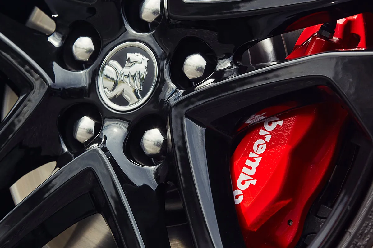 Red Brembo brake caliper visible through black alloy wheel of a Holden VF Commodore SS with Holden lion centre cap