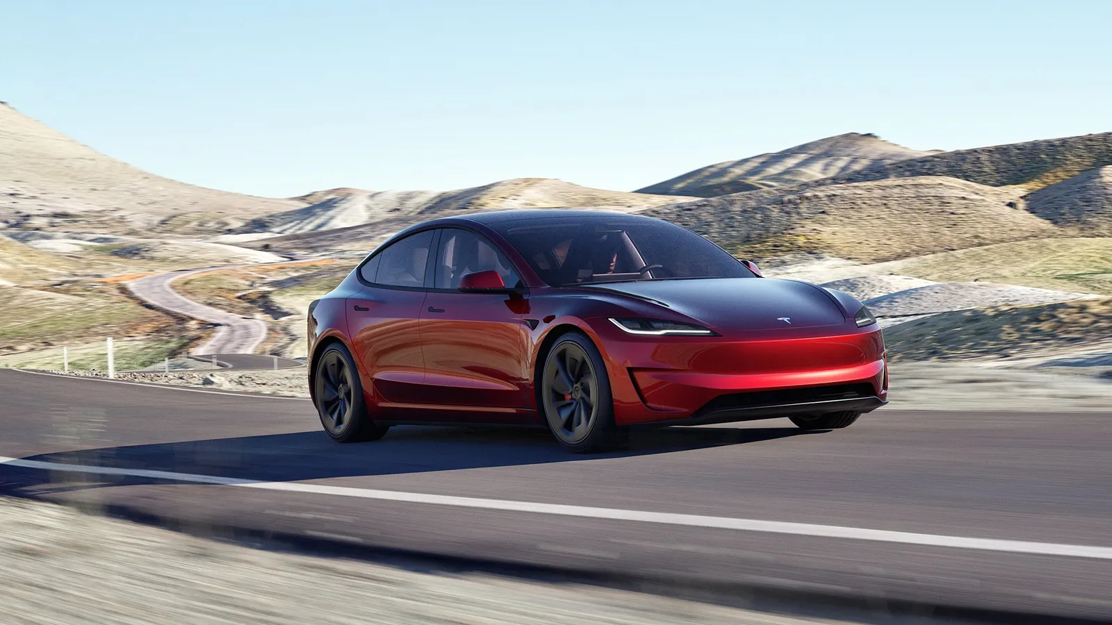 Tesla Model 3 Performance in Ultra Red driving on a winding mountain road