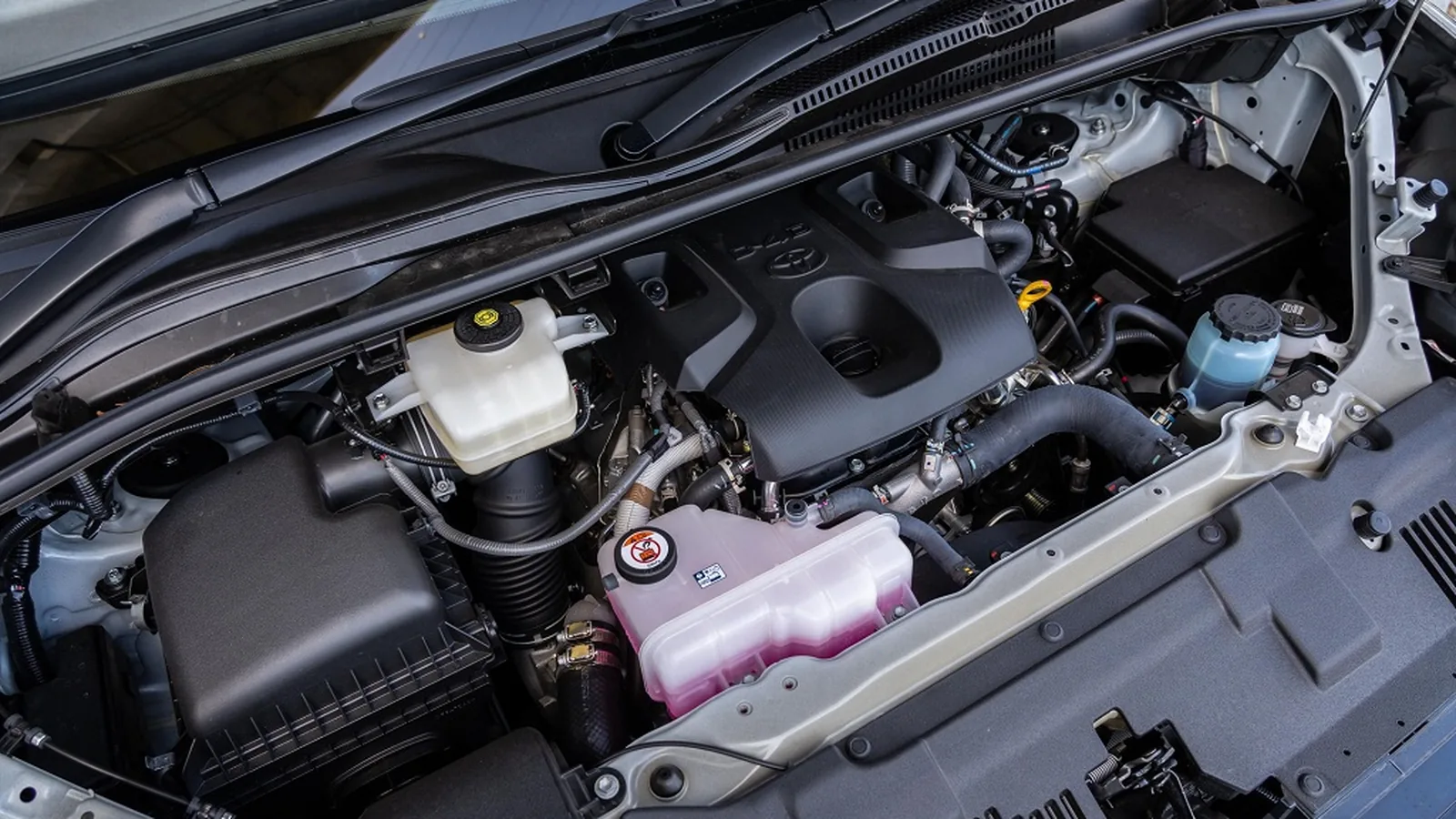 Engine bay of a Toyota HiAce showing the 2.8-litre four-cylinder turbo-diesel and pink long-life coolant tank