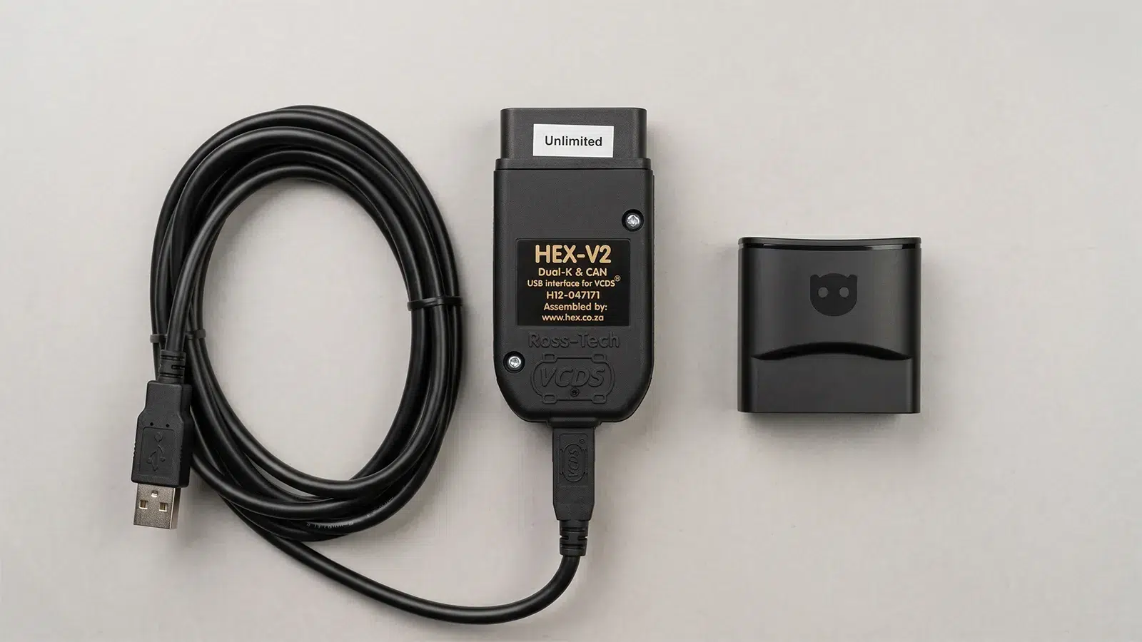 vcds-hex-v2-vs-obdeleven-v3-comparison VCDS HEX-V2 Unlimited USB diagnostic cable alongside an OBDeleven V3 Bluetooth adapter on a neutral grey background