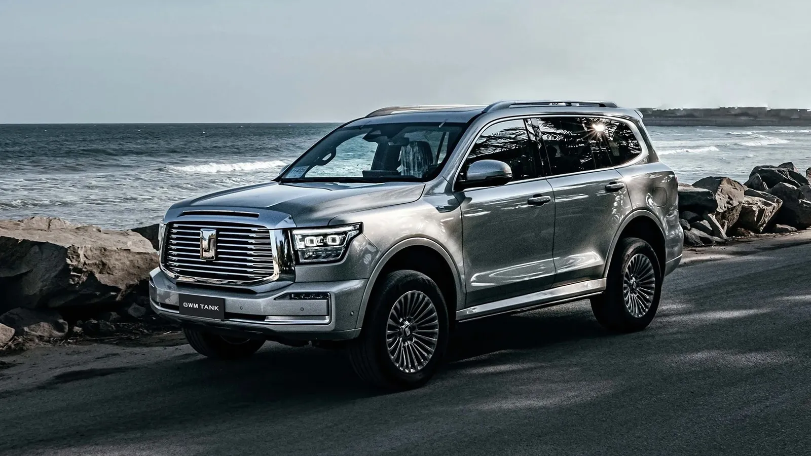 Silver GWM Tank 500 parked on a coastal road beside rocks and the ocean