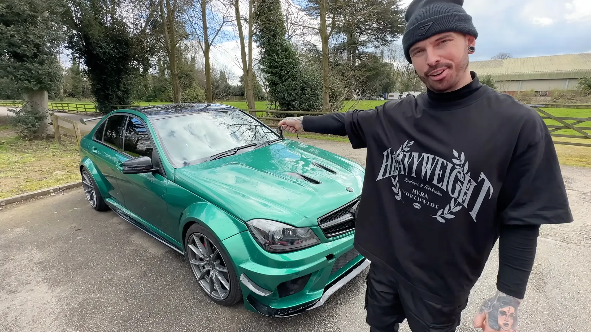Mat Armstrong beside a finished emerald-green modified Mercedes-AMG sedan, the polished result of a salvage rebuild