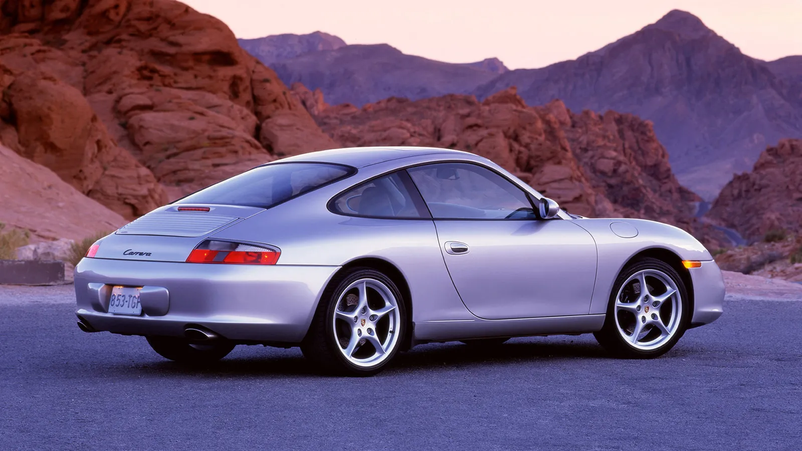 Silver Porsche 911 996 Carrera rear three-quarter view in desert country at dusk