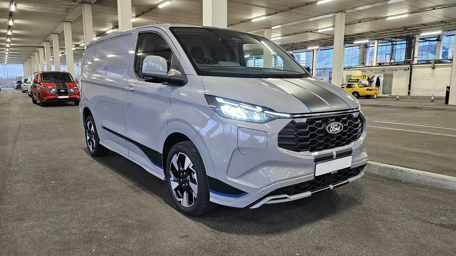 Silver Ford Transit Custom Sport panel van with bonnet stripes parked in a multi-storey car park