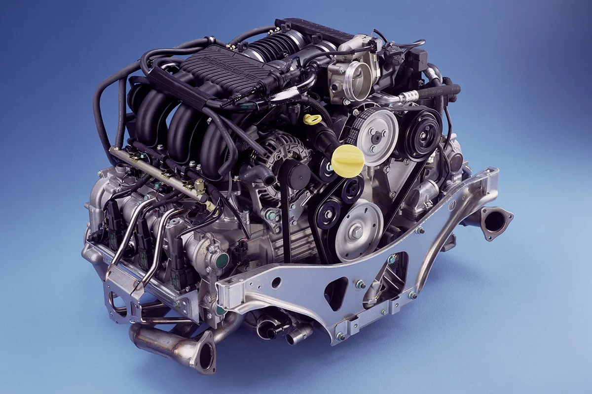 Porsche M96 flat-six engine and subframe assembly photographed out of the car on a blue background
