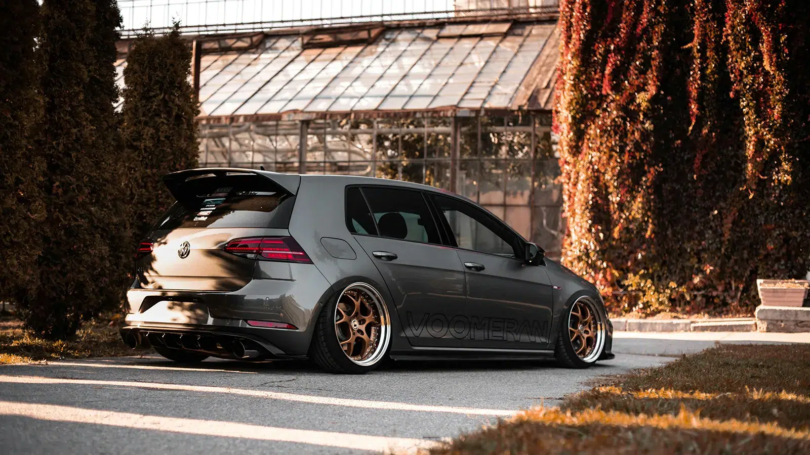 Heavily modified grey Volkswagen Golf Mk7.5 on bronze split-rim wheels with Voomeran aero, rear three-quarter view