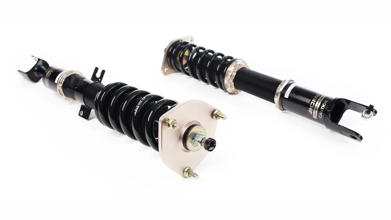 Two BC Racing coilover units showing threaded bodies, camber plate top mount and damping adjuster knob
