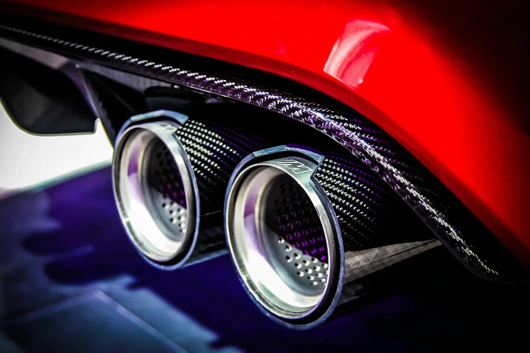 bmw-competition-m-exhaust Close-up of quad chrome exhaust tips and a carbon fibre diffuser on a red BMW M car