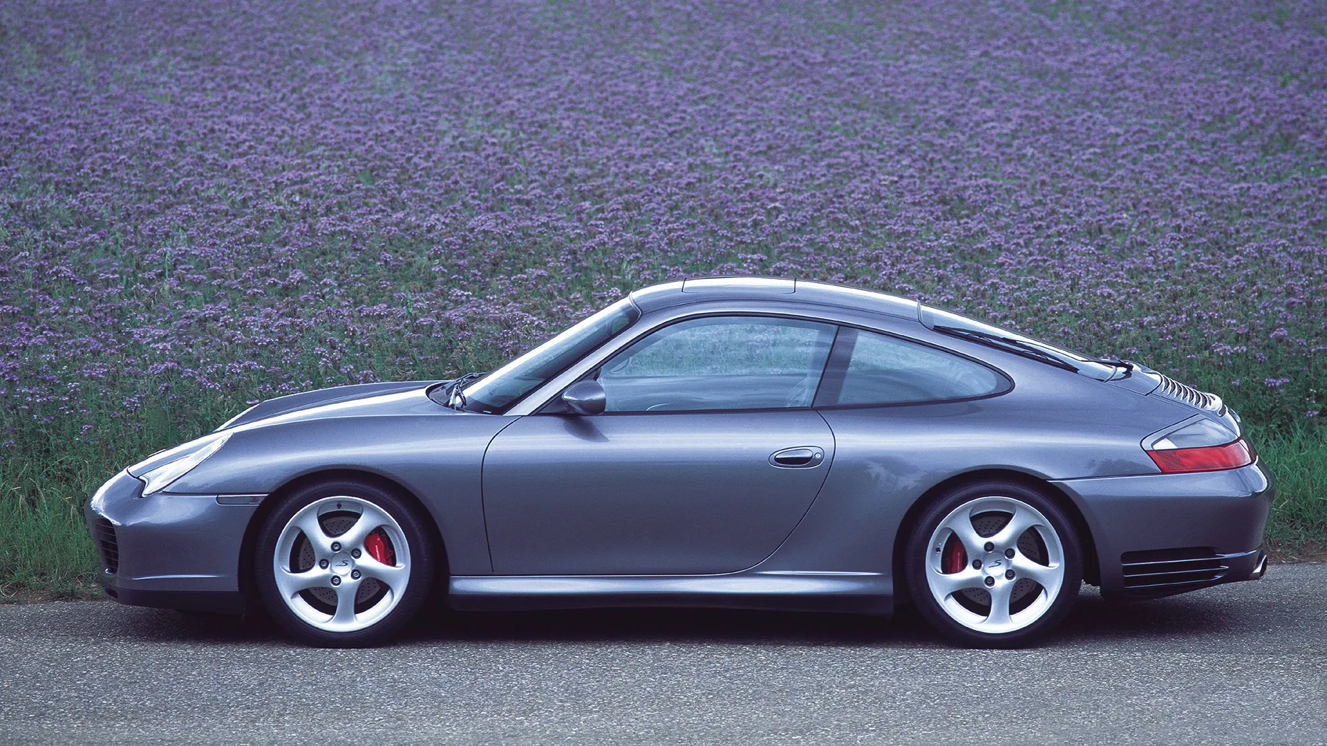 Grey Porsche 911 996 Carrera 4S parked beside a lavender field, full side profile