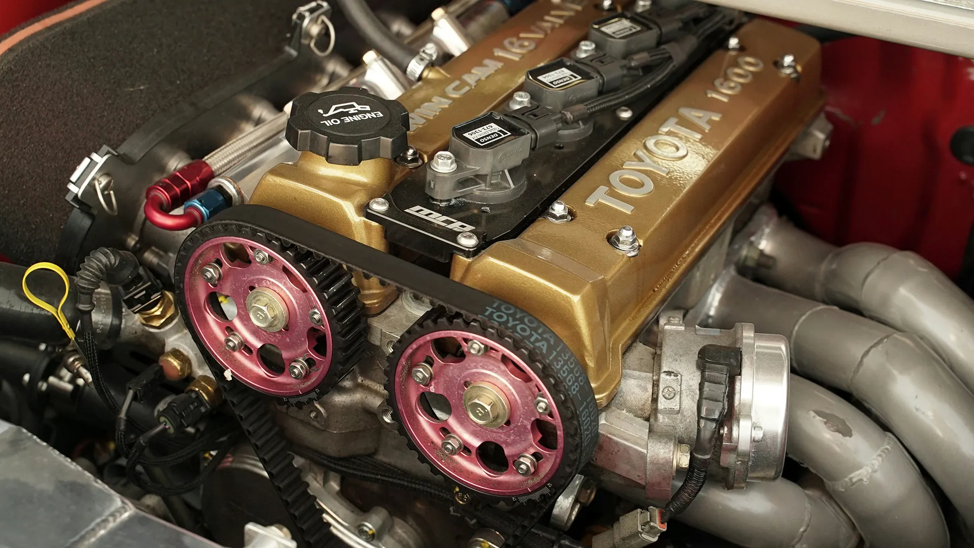 Toyota 4A-GE twin-cam engine with exposed timing belt and pink aftermarket adjustable camshaft pulleys