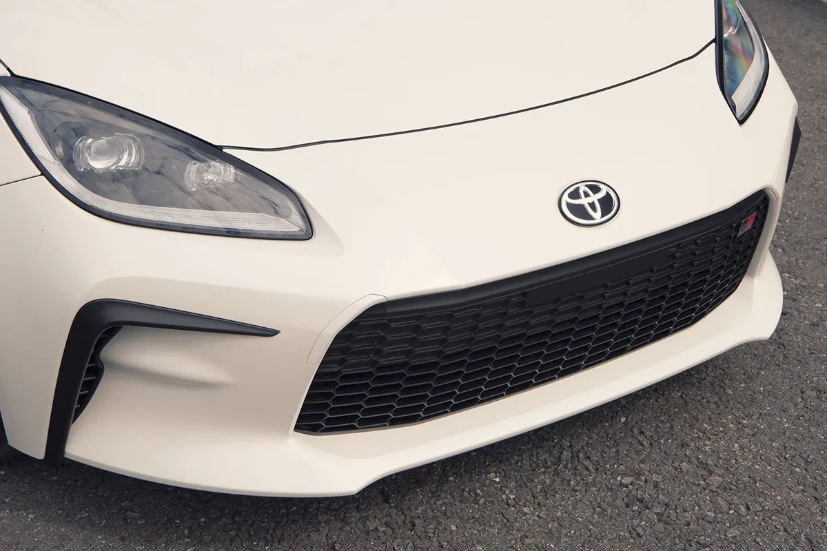 Front detail of a cream Toyota GR86 showing the Toyota badge, honeycomb grille and front lip