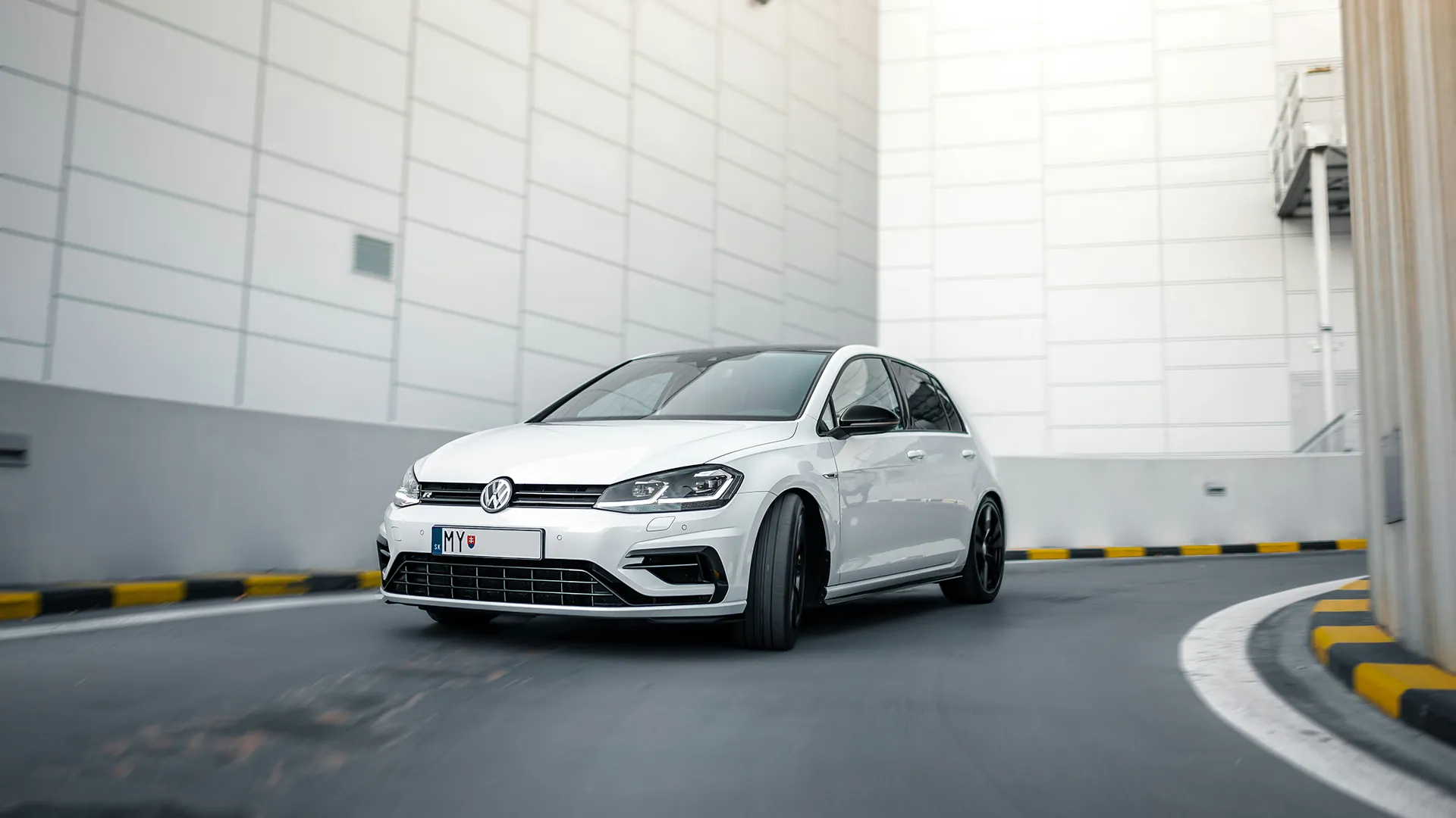 White Volkswagen Golf R Mk7.5 cornering on a car park ramp, front three-quarter view