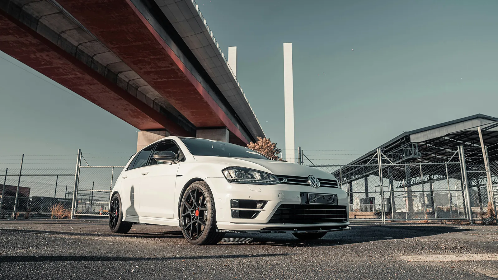 White Volkswagen Golf R Mk7 parked beneath the Bolte Bridge in Melbourne, low front three-quarter view
