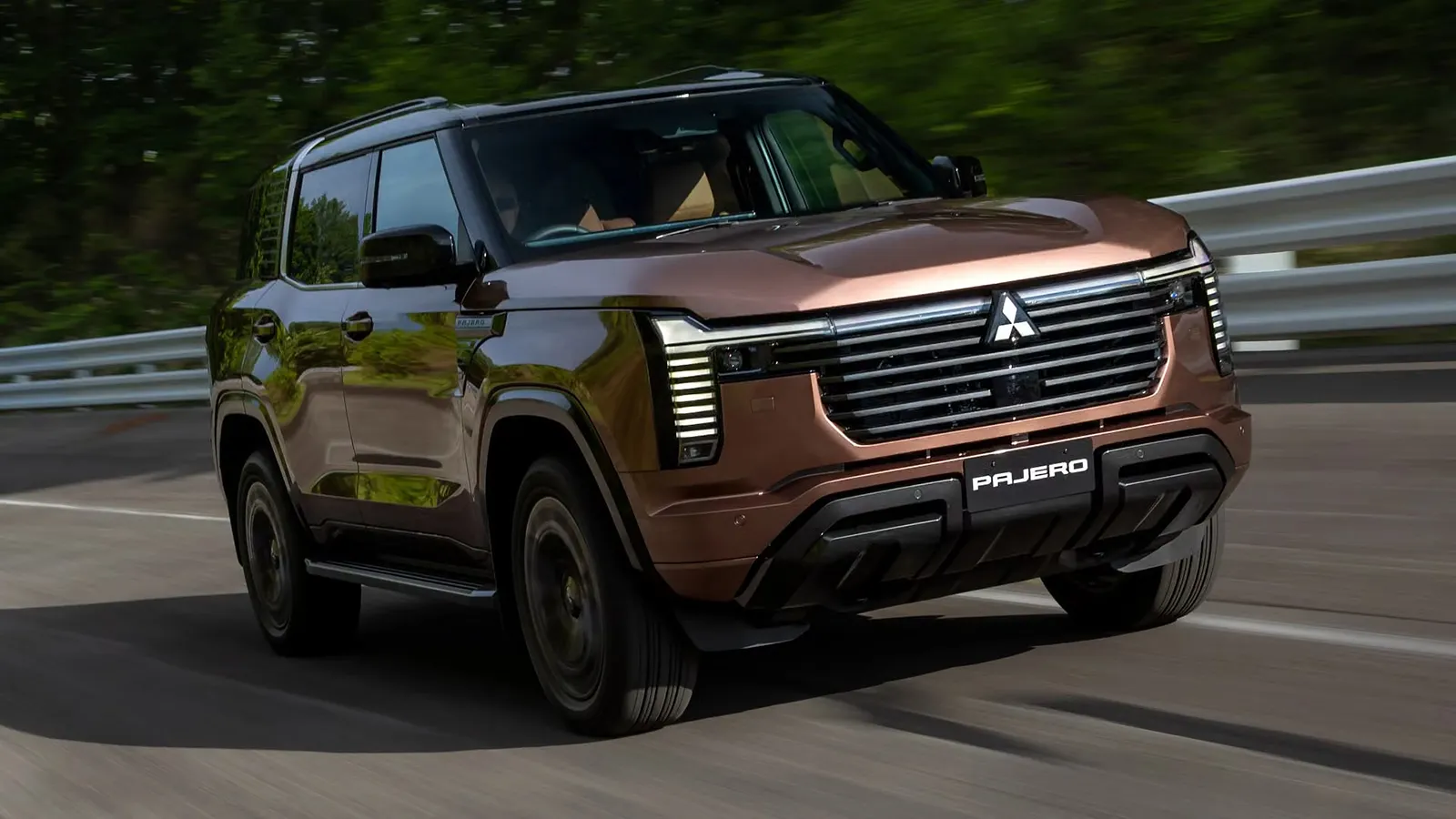 New Mitsubishi Pajero driving on a sealed road, front three-quarter view with motion blur in the background
