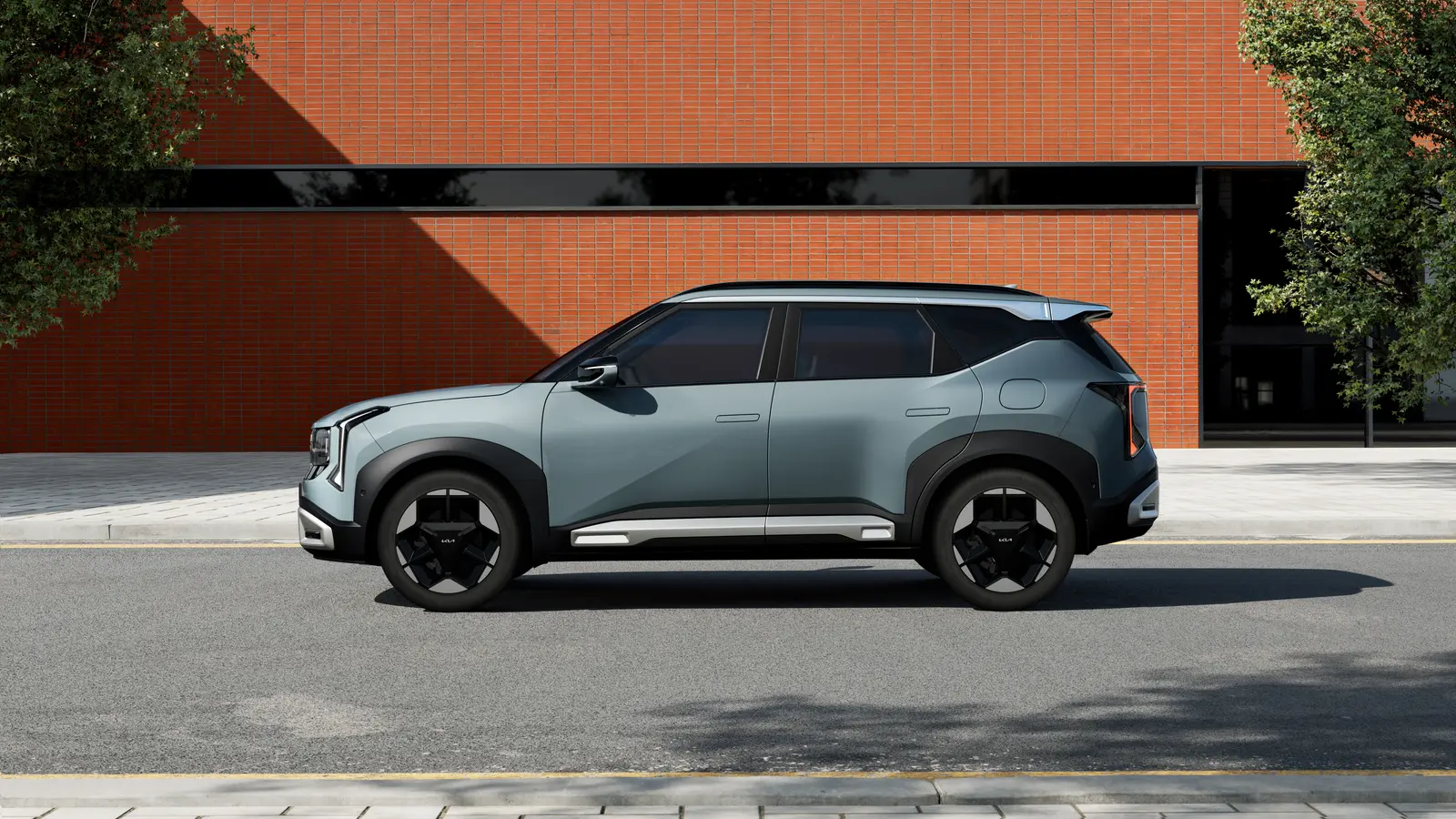 Side profile of a light green 2027 Kia Seltos small SUV parked in front of a red brick building