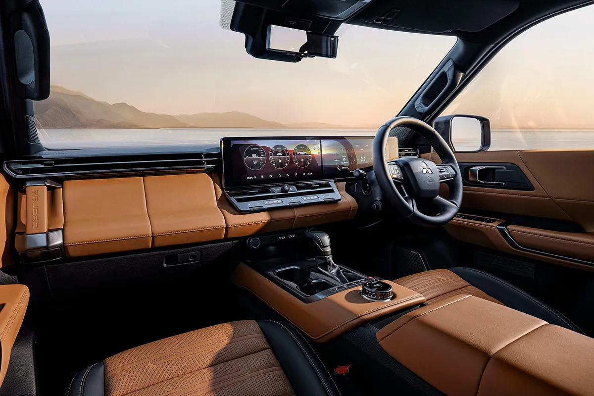 Interior of the new Mitsubishi Pajero showing dual widescreen displays, tan leather trim and the rotary drive mode dial