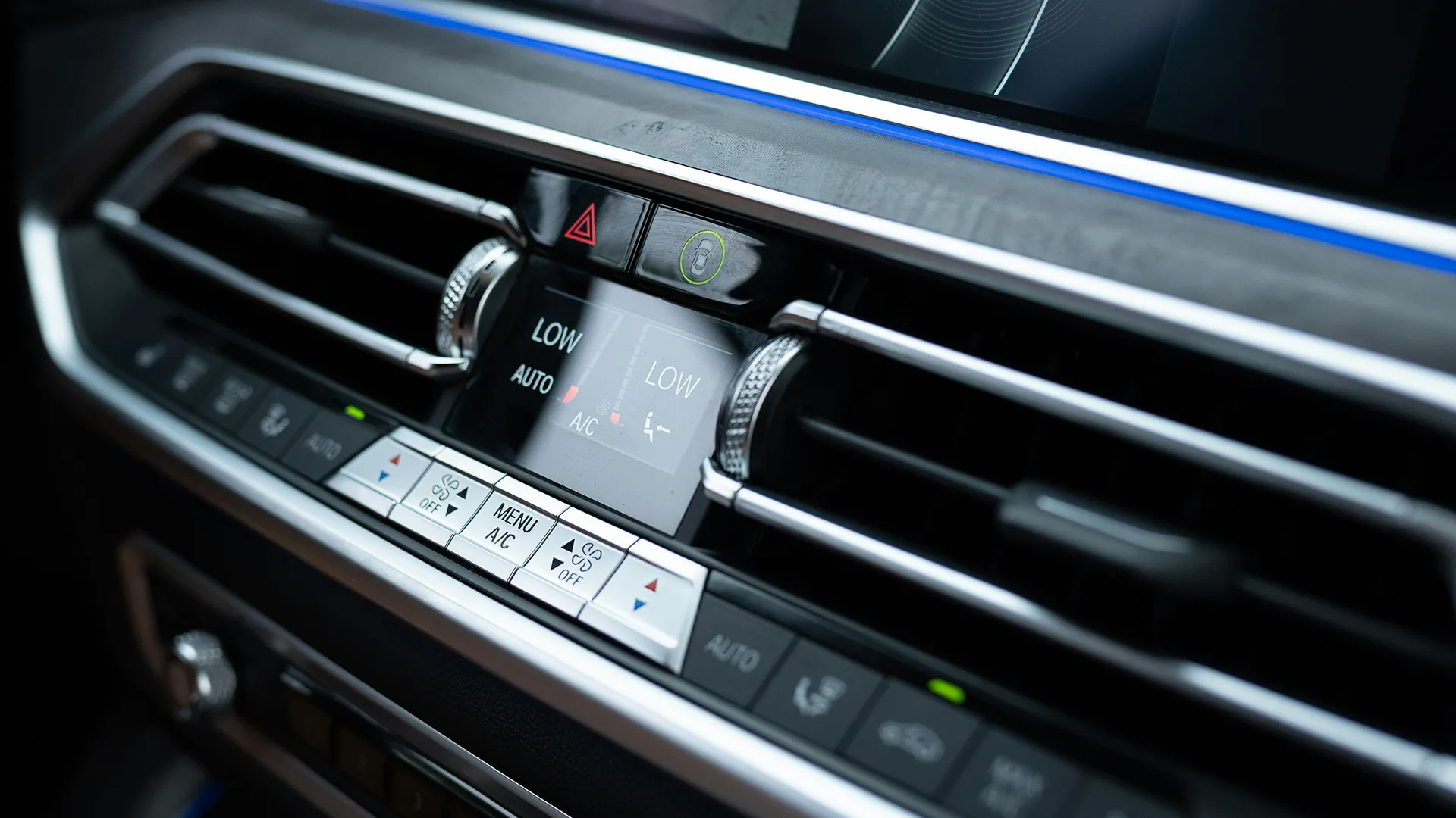 bmw-car-air-con-vents Close-up of a modern car's dual-zone climate control panel set to LOW with the A/C button visible